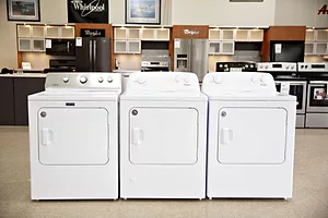 THREE DRYER APPLIANCES SIT IN A ROW IN A STORE