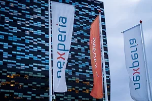 BANNERS BEARING THE NEXPERIA LOGO FLY OUTSIDE A MODERNIST OFFICE BLOCK