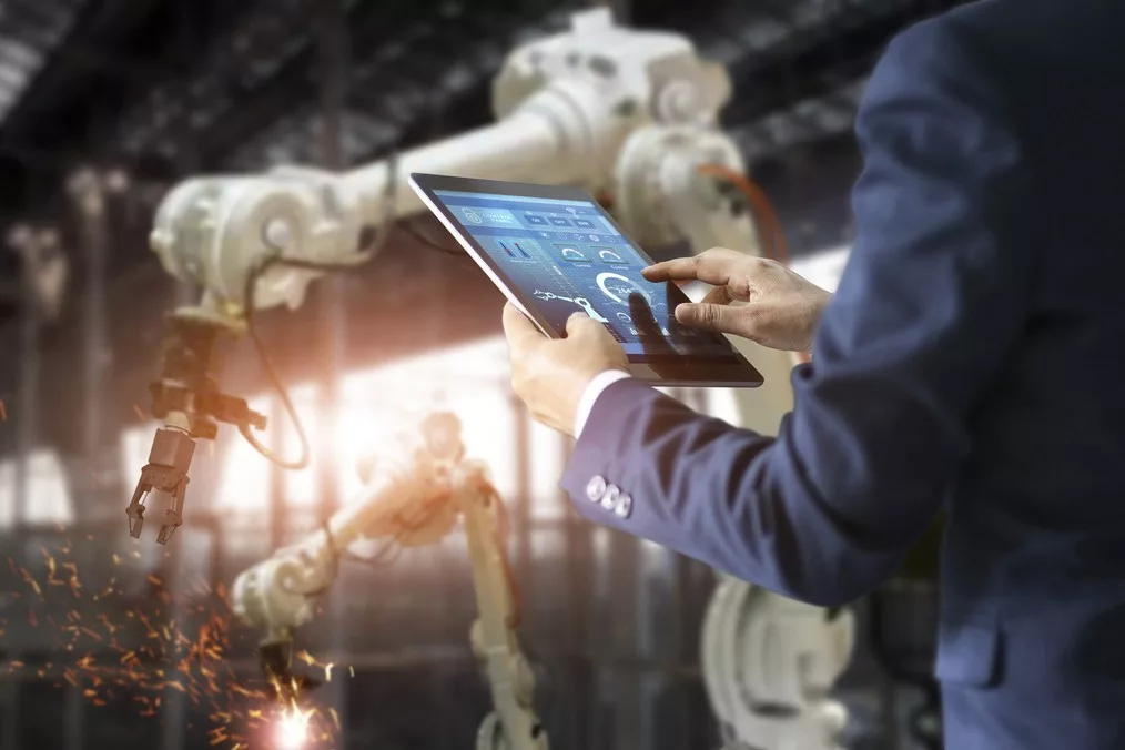 engineer using tablet check and control automation robot arms machine in intelligent factory