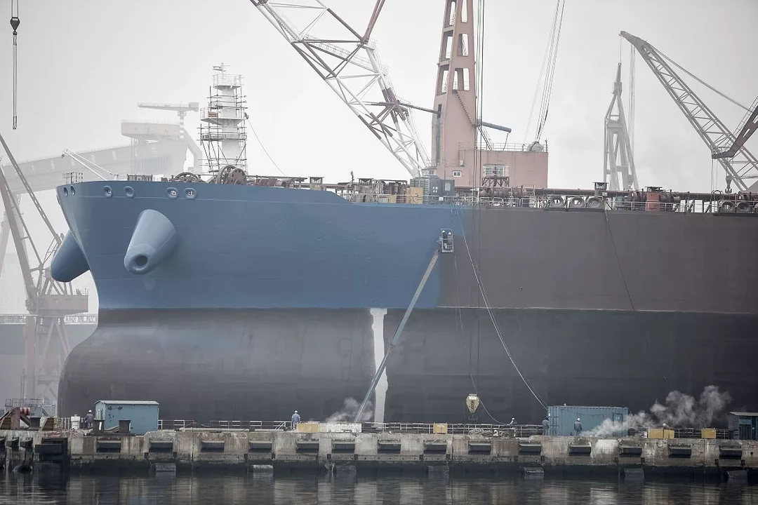 A LARGE SHIP WITH A BULBOUS BOW SITS IN A SHIPYARD