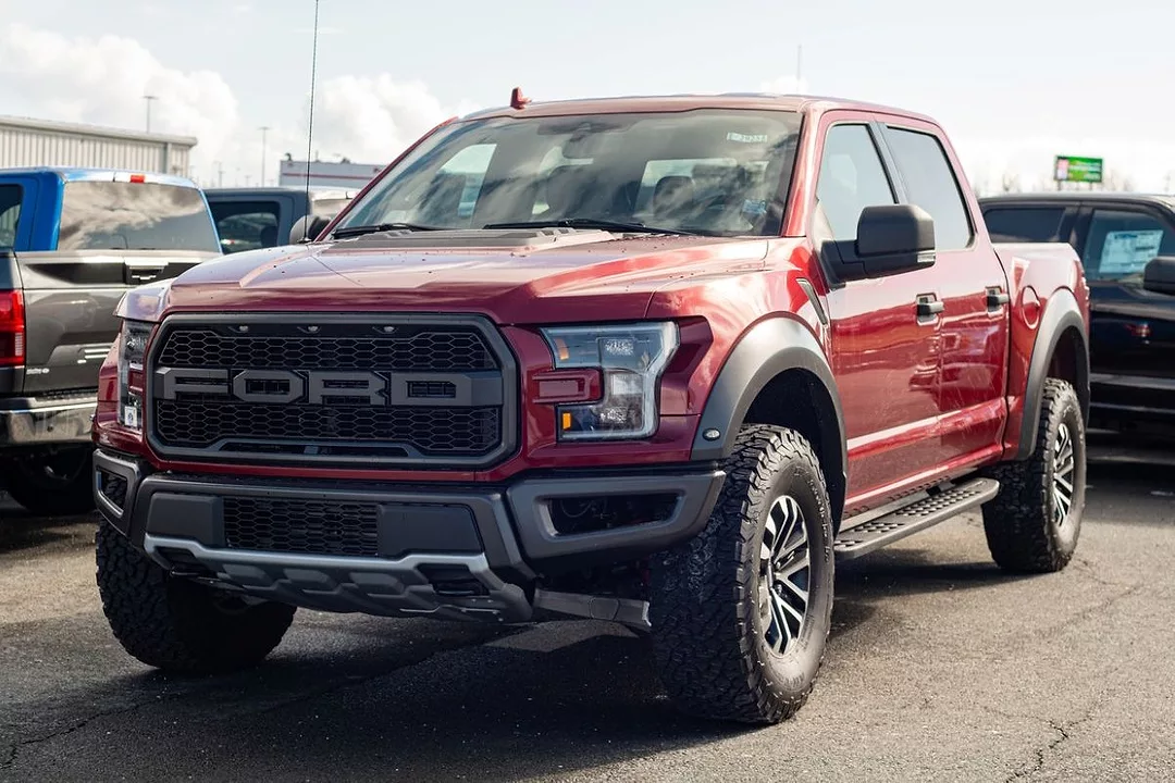 A LARGE RED PICKUP TRUCK BEARS THE FORD LOGO ON ITS GRILLE