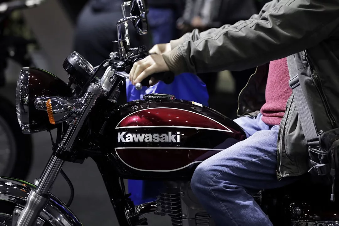 A man in jeans and a grey jacket sitting on a black motorcyle