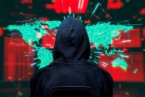 A Computer Hacker sits in front of a computer with world map hologram on surveillance system