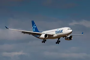 A PLANE BEARING THE AIR TRANSAT LOGO FLIES THROUGH THE SKY
