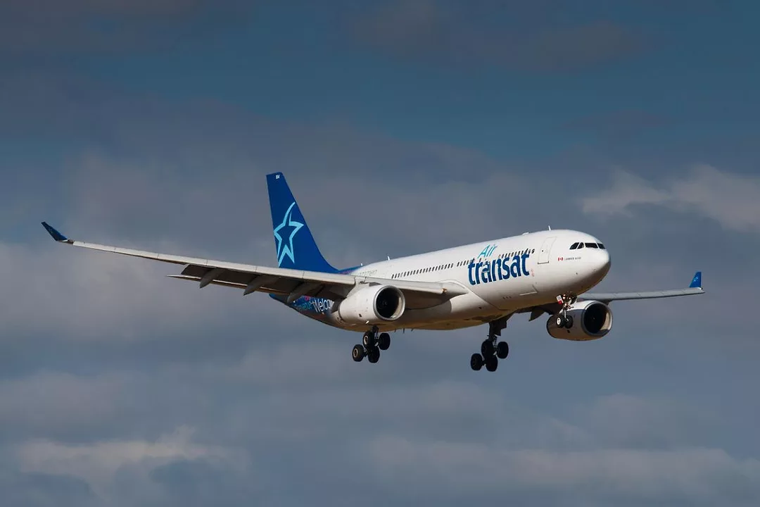 A PLANE BEARING THE AIR TRANSAT LOGO FLIES THROUGH THE SKY