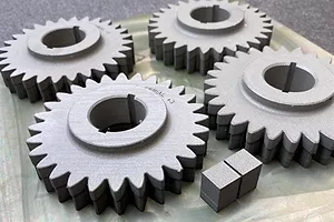 FOUR GREY GEAR WHEELS SIT ON A WORK BENCH