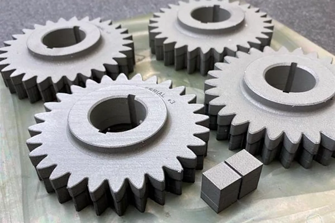 FOUR GREY GEAR WHEELS SIT ON A WORK BENCH