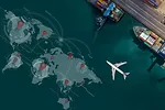 A visualization of a world map on the surface of a body of water next to a port, where two large container ships are docked