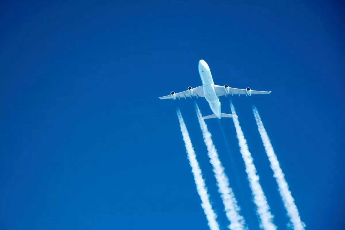 A PLANE FLYING HIGH IN A  BLUE SKY LEAVES VISIBLE WHITE TRAILSjpg
