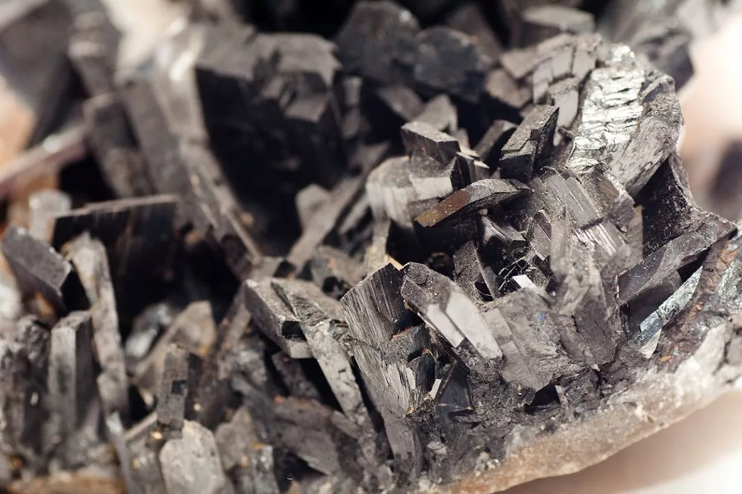 A CLOSE UP PHOTO OF A PATCH OF DARK GREY, CRYSTALLINE MINERAL DEPOSITS