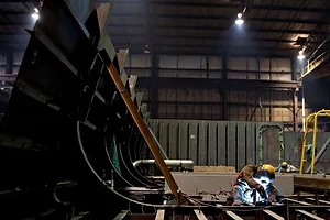 A WELDER WORKS ON THE FUTTOCKS OF A SHIP UNDER CONSTRUCTION