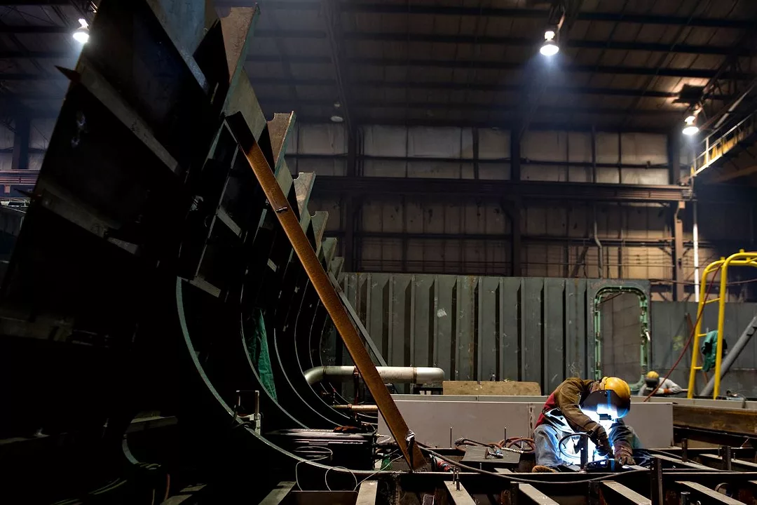 A WELDER WORKS ON THE FUTTOCKS OF A SHIP UNDER CONSTRUCTION