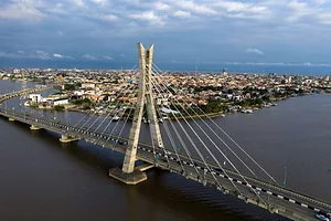 A LONG ROAD BRIDGE CROSSES A LAGOON IN A CITY