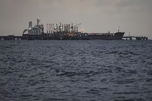 A grey container ship docked in choppy waters on a cloudy day
