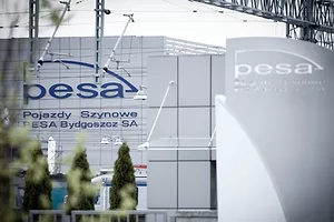 OVERHEAD TRAIN INFRASTRUCTURE FRAMES A COMMERCIAL BUILDING BEARING THE NAME PESA