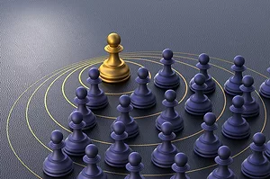 A GOLD CHESS PIECE SITS AMONG MANY BLACK CHESS PIECES