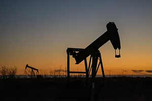 A large oil rig drilling into the ground at sunset