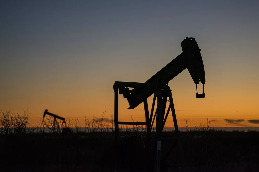 A large oil rig drilling into the ground at sunset