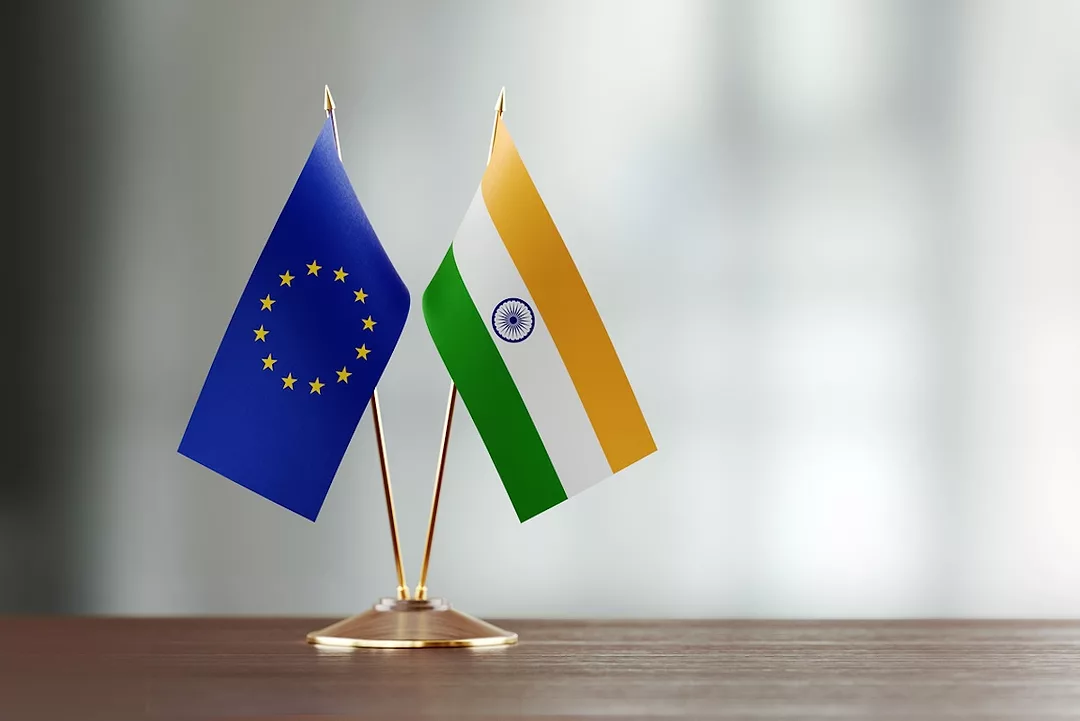 The EU and Indian flags standing next to each other on a wooden desk