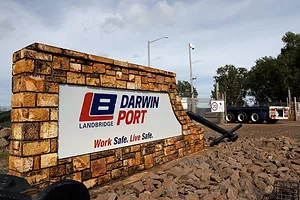 A brown stone wall with a white sign that reads "Darwin Port" in blue and red lettering