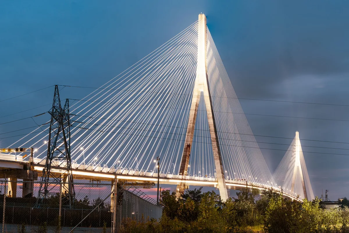 A white bridge with two wishbone-shaped spans connecting a series of wires that extend across the length of the span
