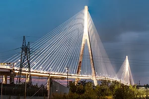 A white bridge with two wishbone-shaped spans connecting a series of wires that extend across the length of the span