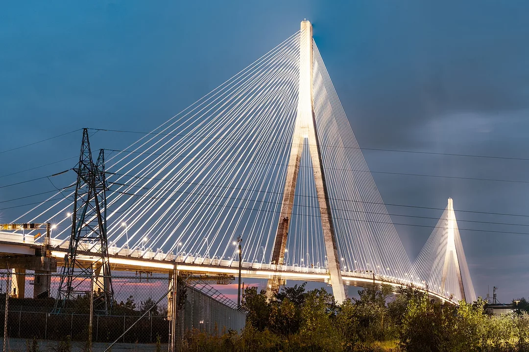 A white bridge with two wishbone-shaped spans connecting a series of wires that extend across the length of the span