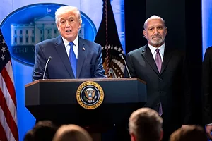 A MAN IN A SUIT AND TIE STANDS AT A PODIUM BEARING THE SEAL OF THE PRESIDENT OF THE UNITED STATES