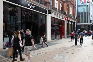 PEOPLE WALK PAST A STORE FRONT, A BRITISH FLAG HANGING ABOVE