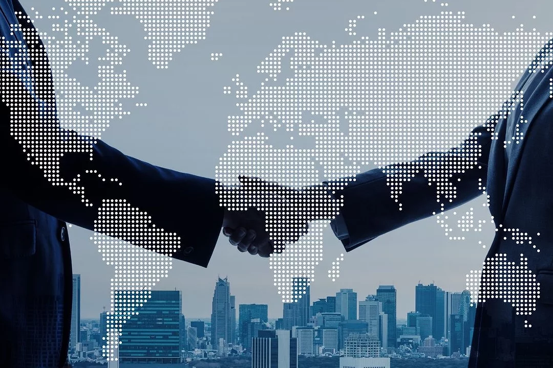 A GRAPHIC SHOWS TWO ARMS SHAKING HANDS OVER A MAP OF THE WORLD