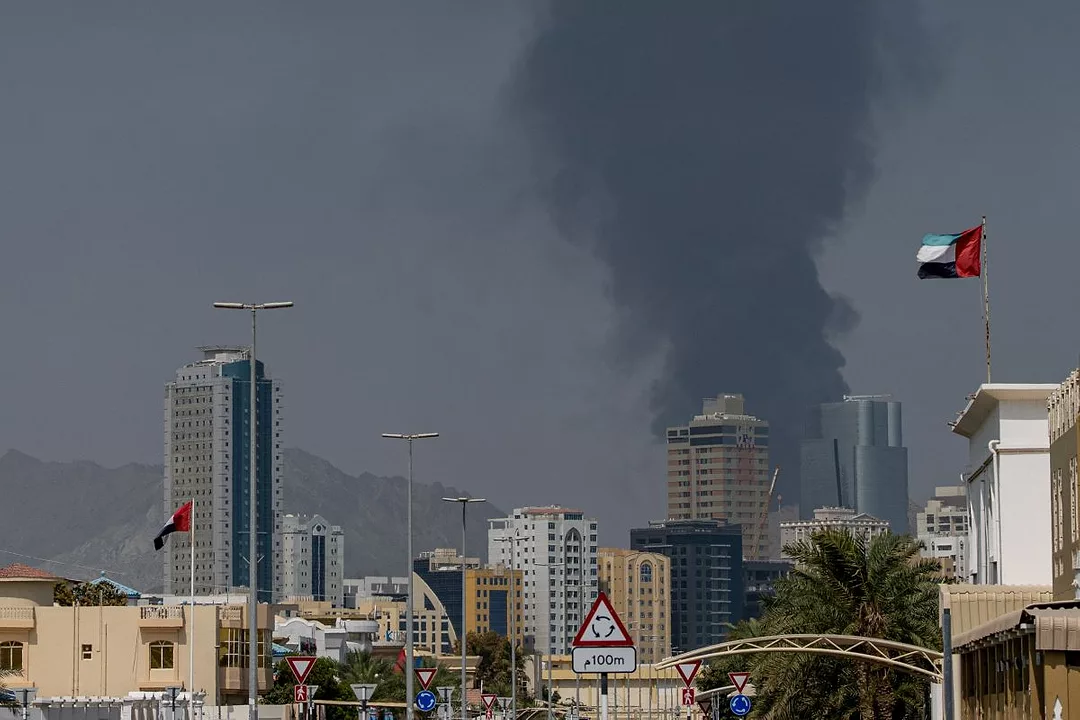AN UGLY PLUME OF DARK GREY SMOKE IN THE DISTANCE RISES ABOVE A MODERN CITYSCAPE
