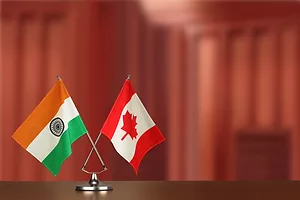 The Indian and Canadian flags posed together on a desk against a blurred red background