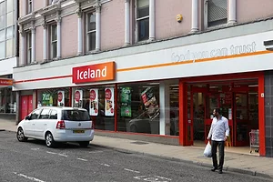 A grocery storefront with a sign that reads "Iceland" in white lettering on a red background