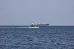 A red and black container ship in open ocean