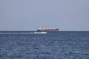 A red and black container ship in open ocean