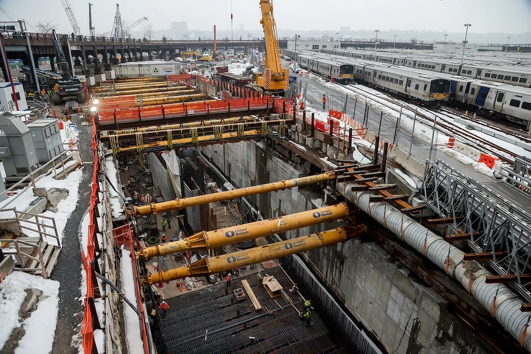 A concrete tunnel dug into the ground with yellow scaffolding along the top
