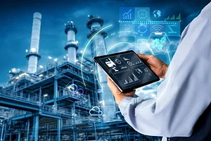 A MONTAGE IMAGE OF A MAN OPERATING A TABLET COMPUTER SUPER-IMPOSED ON A PHOTO OF THE EXTERIOR OF A FACTORY