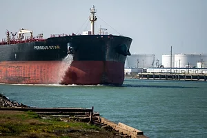 A LARGE OIL TANKER PLIES THE WATERS OF A NARROW PORT ENTRANCE