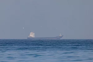 A SHIP IS VISIBLE NEAR THE HORIZON OF AN OPEN SEA