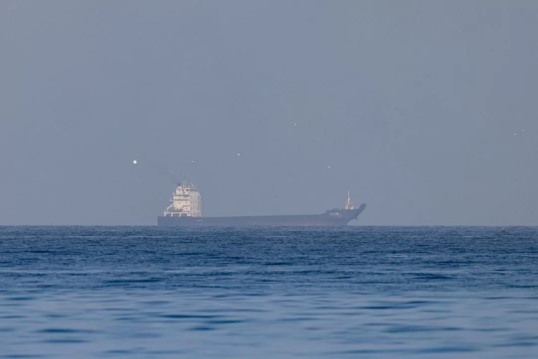 A SHIP IS VISIBLE NEAR THE HORIZON OF AN OPEN SEA