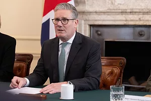 U.K. Prime Minister Keir Starmer sitting at a desk while wearing a black suit and green tie