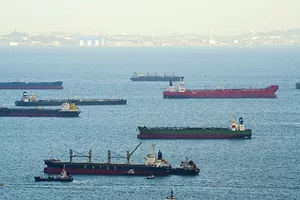 MULTIPLE SHIPS PLY WATERS WITH A COASTLINE IN THE BACKGROUND