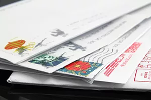 A pile of stamped letters in envelopes sitting on a black table