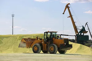 AN ORANGE INDUSTRIAL DIGGER APPROACHES PILES OF YELLOW SAND