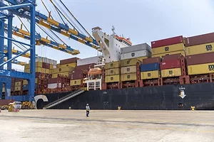 A SHIP LOADED WITH BRIGHTLY COLORED CONTAINERS SITS AT A DOCK