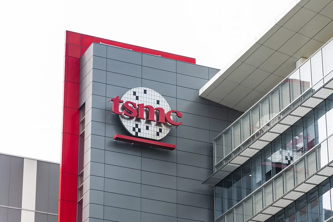 A grey office building with red trim with a logo along the side that reads "TSMC" in red lettering