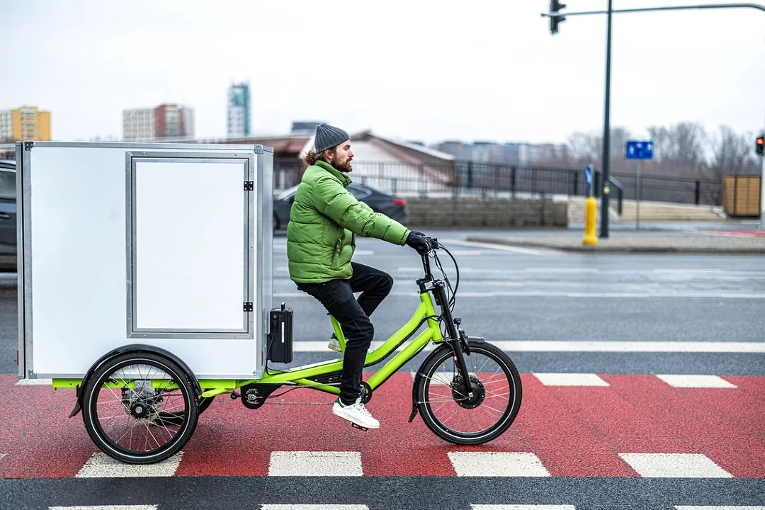 A bicycle courier delivering parcels in the city on a cargo bike