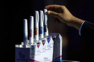A HAND REACHES TOWARD A DISPLAY OF FAT, BRIGHTLY COLORED PENS