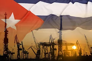 Oil wells silhouetted at sunset, set against a faded image of a Cuban flag