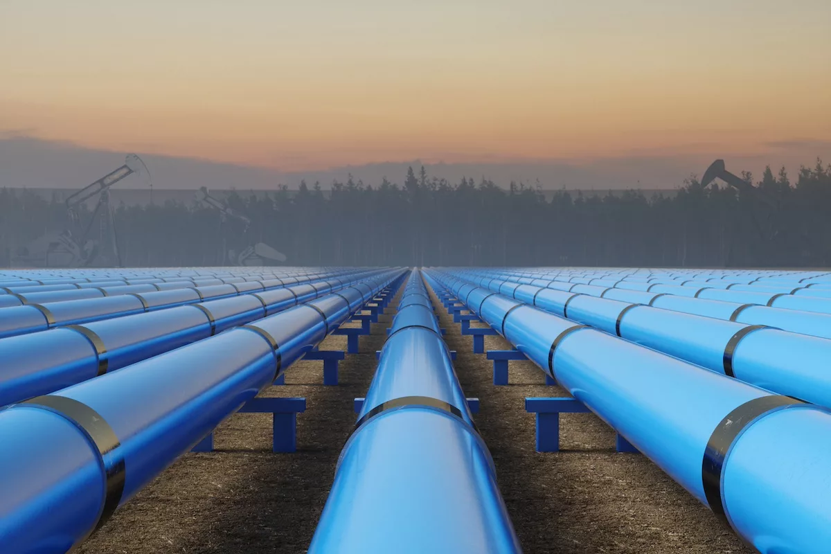 A row of blue oil pipelines in an open field at sunset